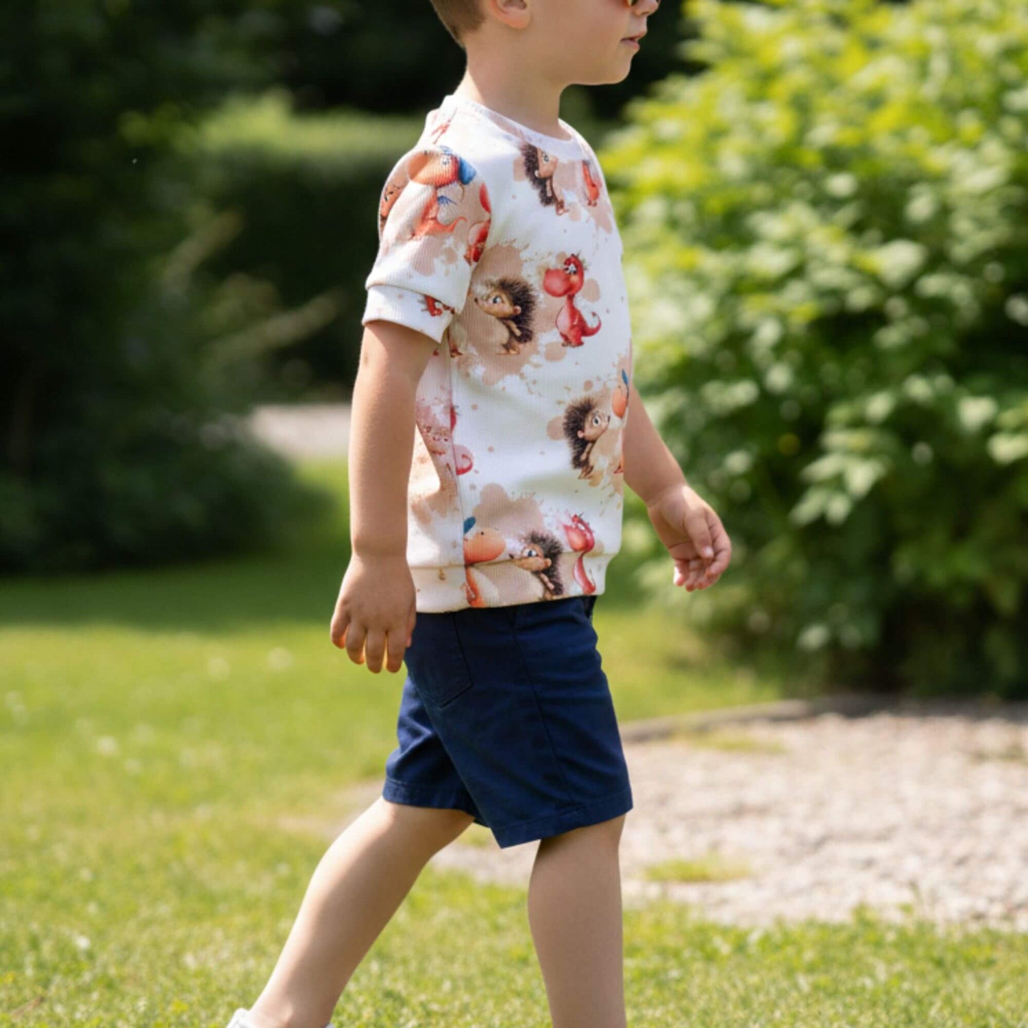 Kind trägt ein Handmade Kinder T-Shirt aus Rib Jersey mit süßem Drachen und Igel Motiv – bequemes Sommer Shirt für Jungen und Mädchen